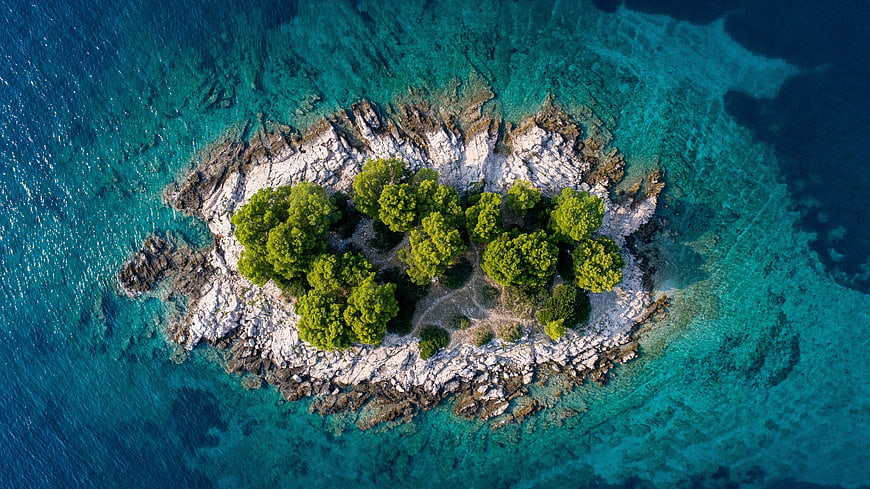 Aerial View of Small Rocky Island with Green Trees in Turquoise Sea