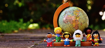 Wooden toy figures representing global diversity standing in front of a globe