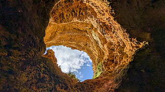 Looking up through a natural rock arch to blue sky