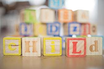 Wooden Alphabet Blocks Spelling Child on Table