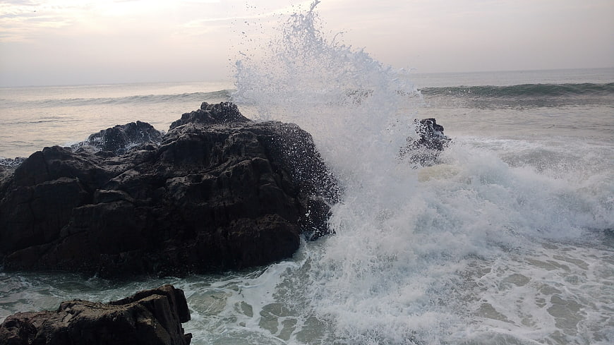 Powerful ocean wave crashing against dark coastal rocks
