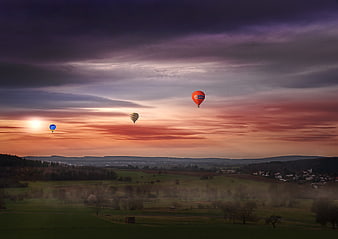 Hot Air Balloons Flying Over Misty Landscape at Sunset