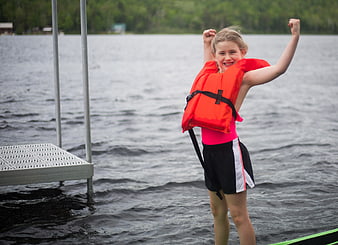 Happy Girl in Life Jacket Celebrating by Lake