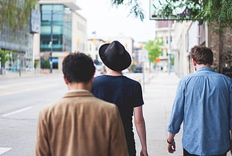 Three men walking away down a city street