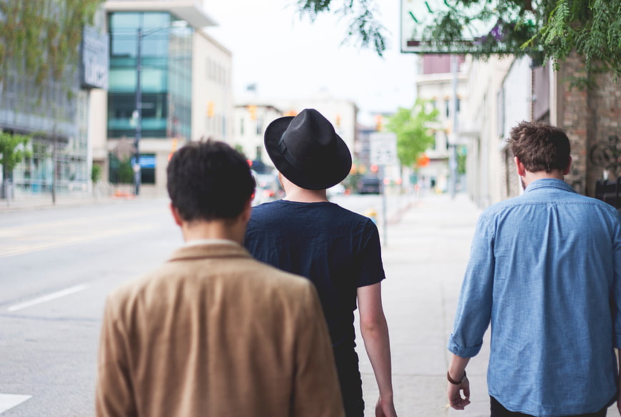 Three men walking away down a city street