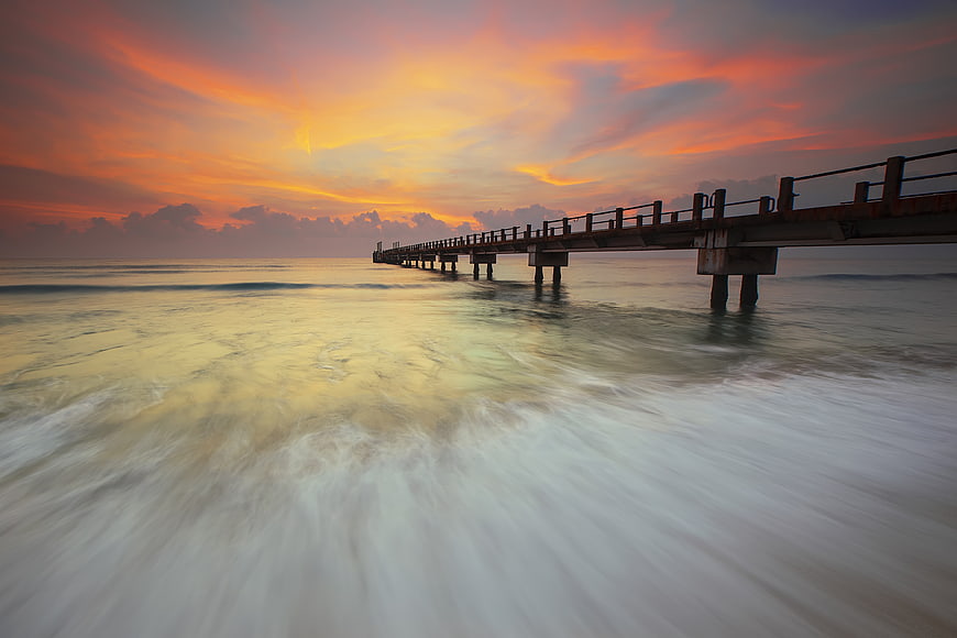 Long Exposure Sunset Over Wooden Pier and Ocean Waves