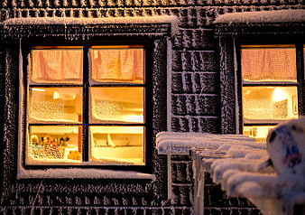 Snow-covered windows with warm interior light at night
