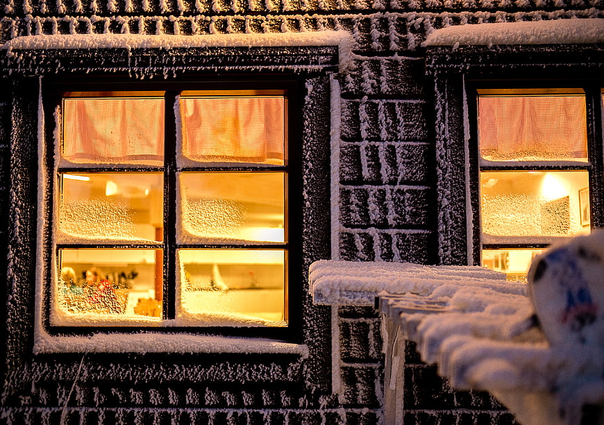 Snow-covered windows with warm interior light at night