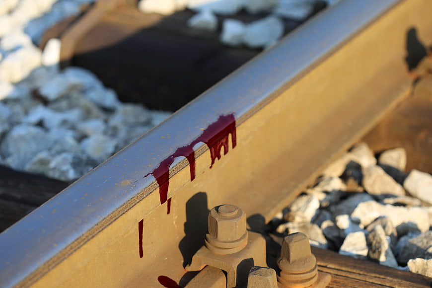 Red liquid dripping on rusty railroad track rail