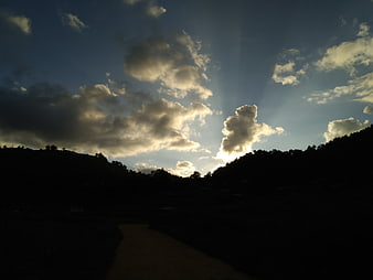 Dramatic Sun Rays Breaking Through Clouds Over Silhouette Hills