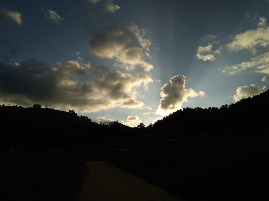 Dramatic Sun Rays Breaking Through Clouds Over Silhouette Hills