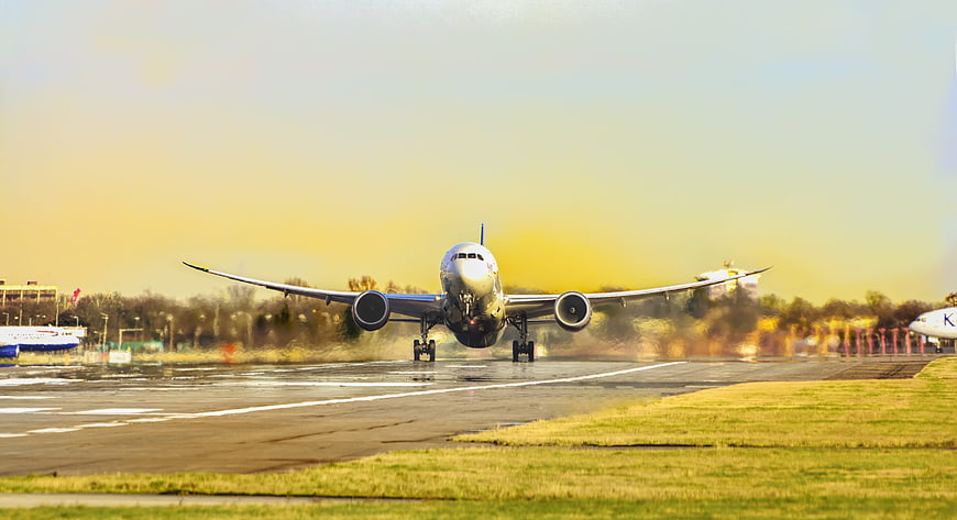 Commercial Airplane Landing on Wet Runway at Sunset