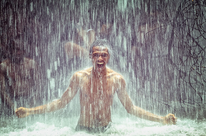 Joyful Shirtless Man Celebrating in Heavy Rain