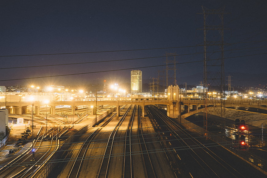 Night view of railway tracks and city skyline with bridge