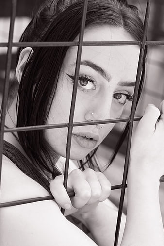 Black and white portrait of woman behind metal bars