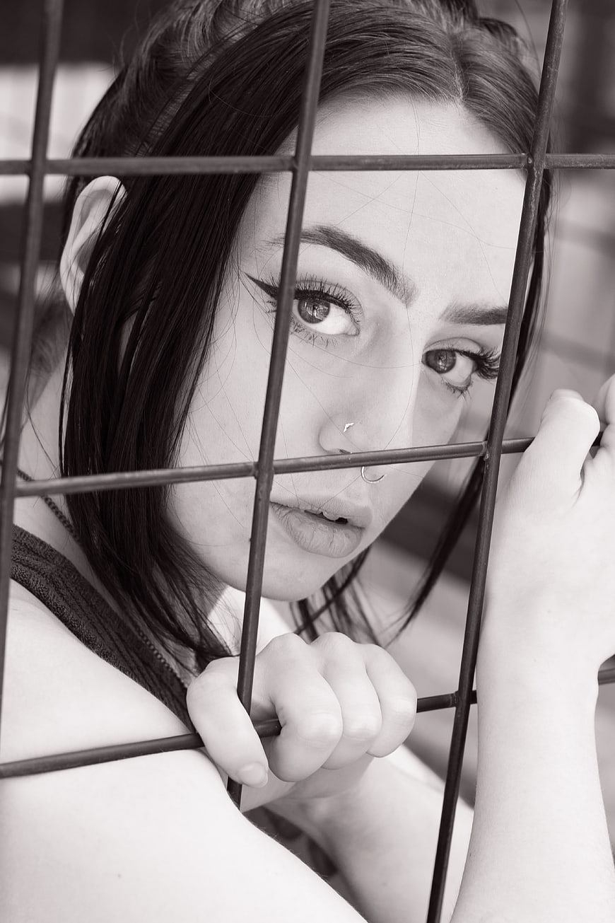 Black and white portrait of woman behind metal bars
