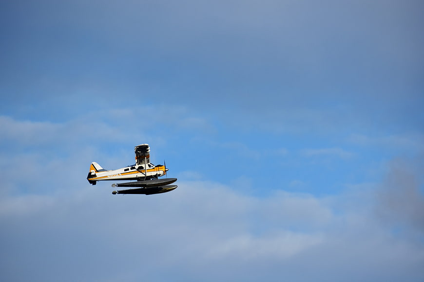 Yellow and white seaplane flying in blue sky