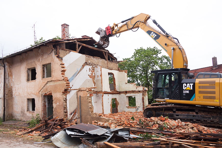 Yellow Excavator Demolishing Old Brick House With Rubble