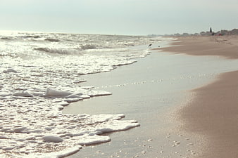 Sunny Beach Shoreline with Gentle Waves and Foamy Water