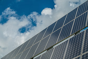 Solar panels against blue sky with clouds