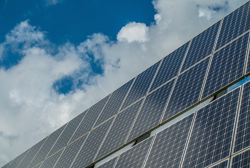 Solar panels against blue sky with clouds
