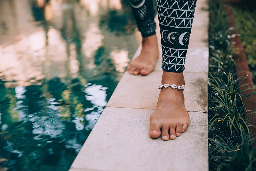 Barefoot woman walking by pool in patterned leggings