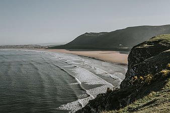 Serene coastal landscape with sandy beach and rolling green hills