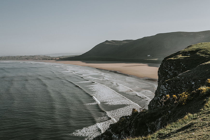 Serene coastal landscape with sandy beach and rolling green hills