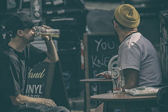 Two Men Drinking Beer at Outdoor Cafe Table