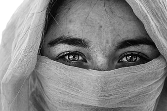 Close-up of woman's eyes behind white veil in black and white