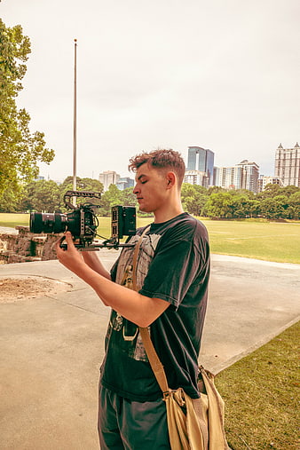 Young Videographer Filming with Cinema Camera in Park