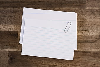 Stack of lined paper with paperclip on wooden desk