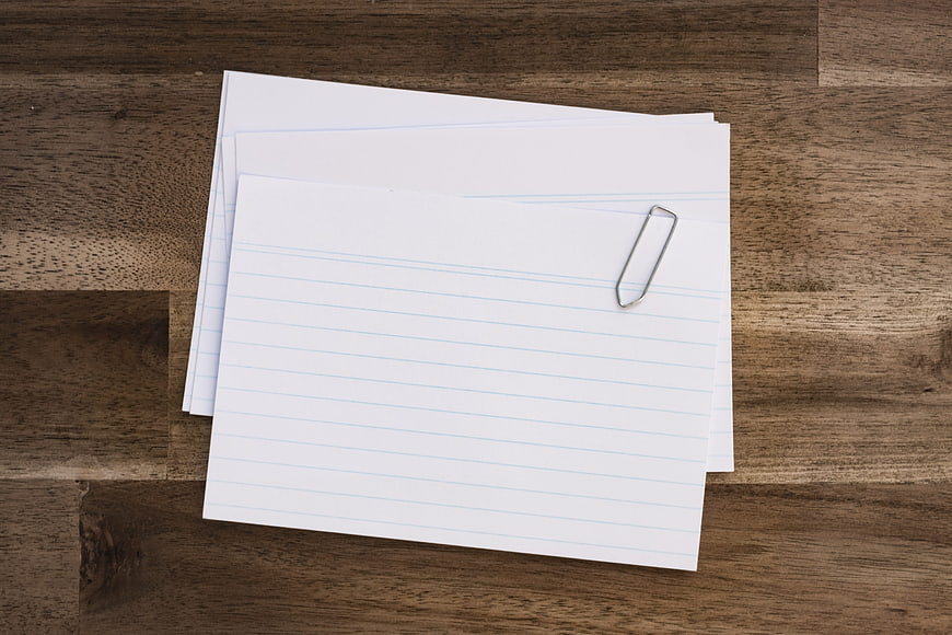 Stack of lined paper with paperclip on wooden desk