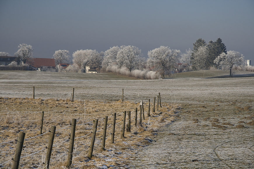 Frosty winter landscape with wooden fence and rural houses