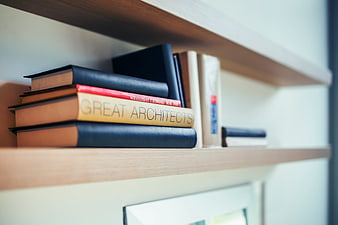 Stack of books on wooden shelf with Great Architects title
