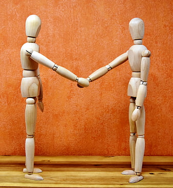 Wooden Mannequins Shaking Hands on Orange Background