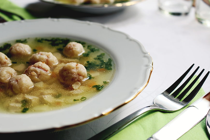 Close-up of meatball soup in white bowl with fork