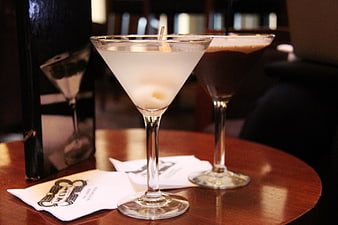 Two elegant cocktails in martini glasses on a wooden bar table