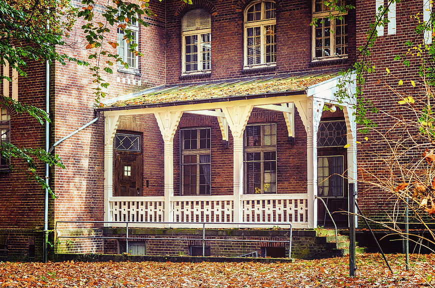 Historic Red Brick House with White Porch in Autumn