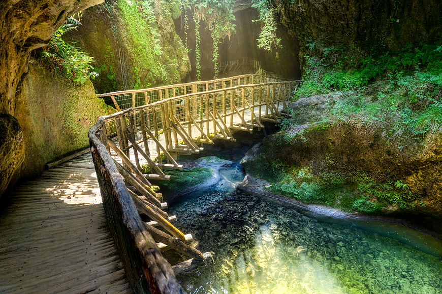 Wooden walkway in Caves Caglieron with clear stream
