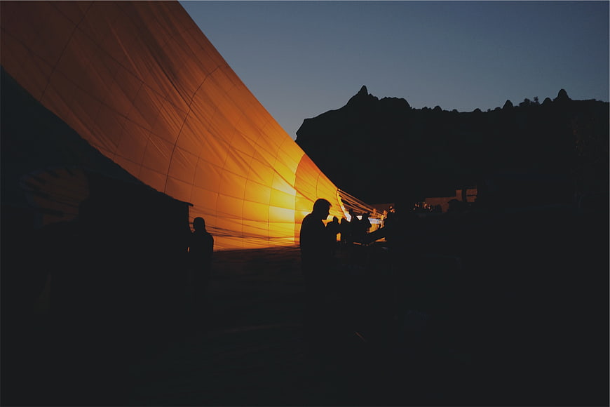 Hot Air Balloon Inflation at Dusk with Silhouetted Crew
