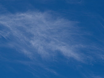 Wispy white clouds against a deep blue sky background