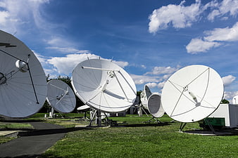 White Satellite Dishes on Green Field Under Blue Sky