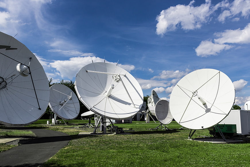 White Satellite Dishes on Green Field Under Blue Sky