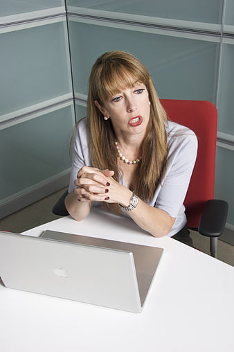 Businesswoman in white top sitting at desk with laptop in modern office
