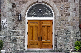 Wooden double doors on historic stone church facade