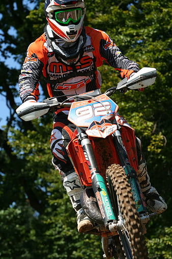 Motocross Rider Jumping Orange Dirt Bike in Forest