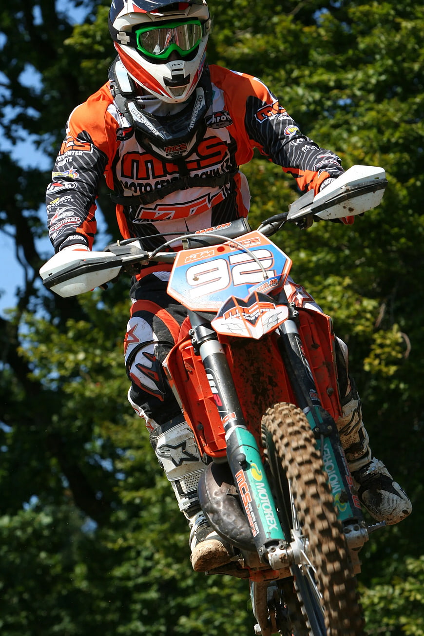 Motocross Rider Jumping Orange Dirt Bike in Forest