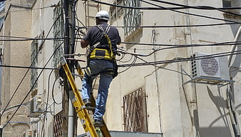 Utility worker repairing cables on a ladder
