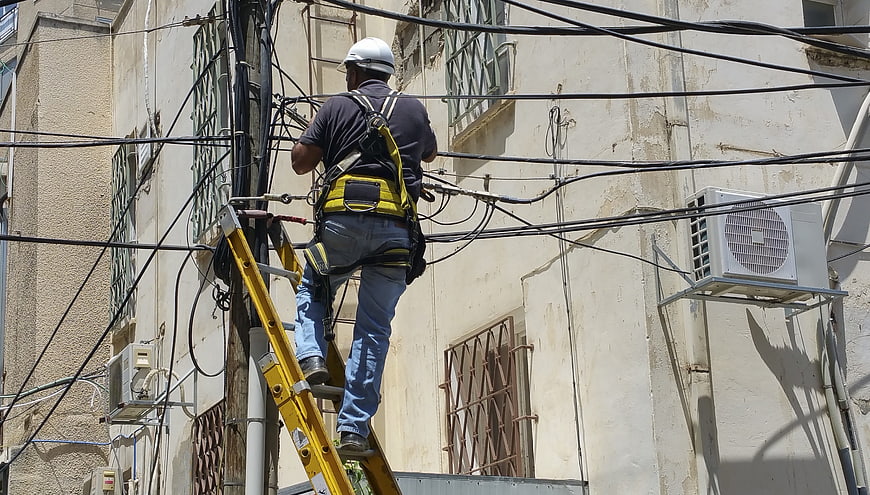 Utility worker repairing cables on a ladder